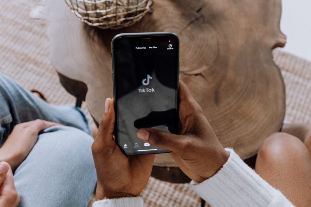 woman holding phone and opening TikTok app in hotel lobby